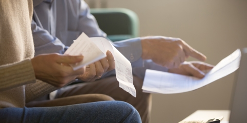 Elderly spouses sitting on couch at home looking at court summons